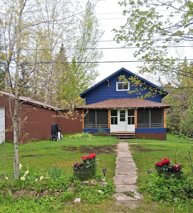3468 W Nye Rd, Hessel, MI 49745 - view of front facade with a sunroom, a front lawn, and roof with shingles