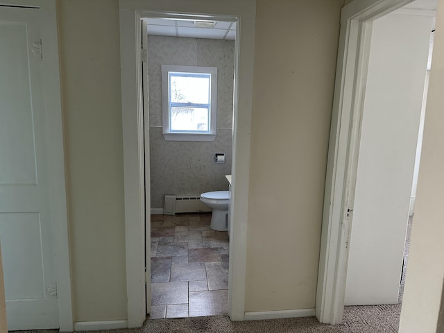 bathroom featuring a baseboard radiator, toilet, and baseboards