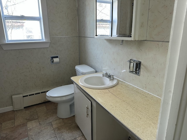 bathroom with toilet, vanity, a baseboard radiator, and a healthy amount of sunlight