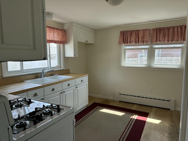 kitchen with a baseboard radiator, a healthy amount of sunlight, white gas range oven, and a sink