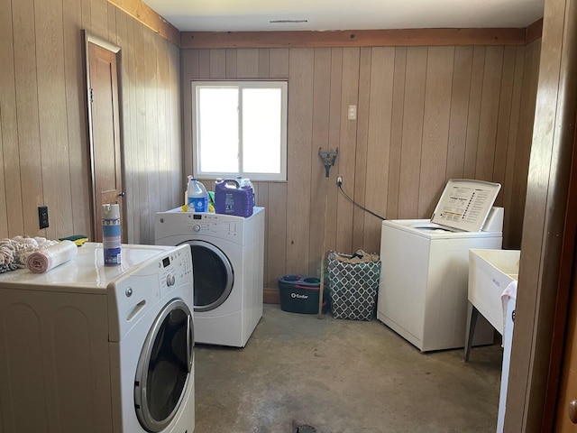 laundry area featuring washing machine and clothes dryer, wood walls, and laundry area
