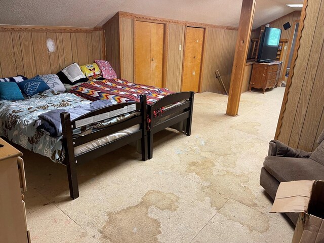 bedroom with wooden walls, vaulted ceiling, and a textured ceiling