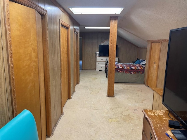 hallway featuring wooden walls and lofted ceiling