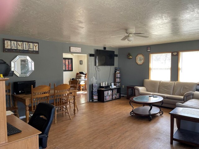 living room featuring wood finished floors, a textured ceiling, and a ceiling fan