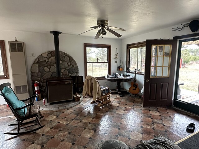 interior space with ceiling fan and a wood stove