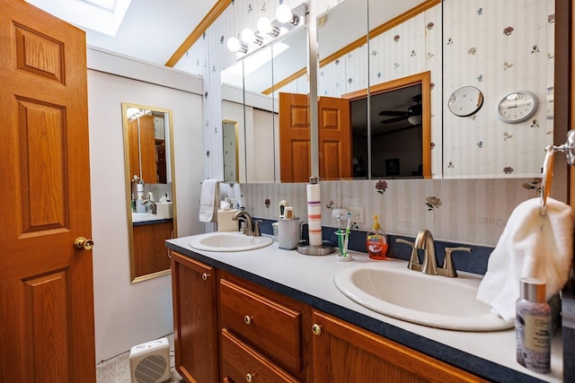 full bathroom with a skylight, wallpapered walls, a sink, and double vanity