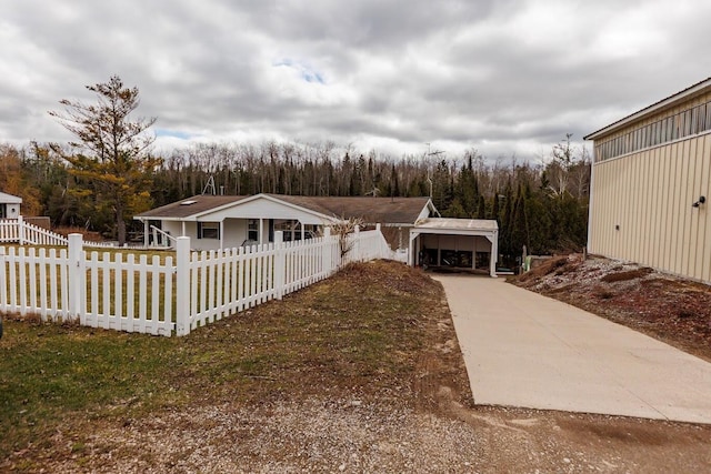 view of front of property with a detached carport, concrete driveway, and a fenced front yard