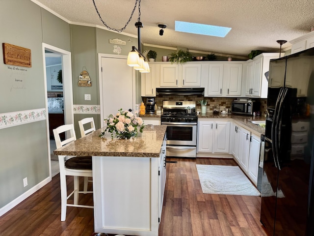 10525 Alpenhof Dr, Grayling, MI 49738 - kitchen featuring appliances with stainless steel finishes, under cabinet range hood, a skylight, white cabinets, and vaulted ceiling