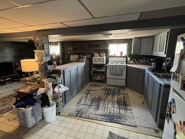 kitchen with gray cabinetry, light countertops, a paneled ceiling, and white appliances