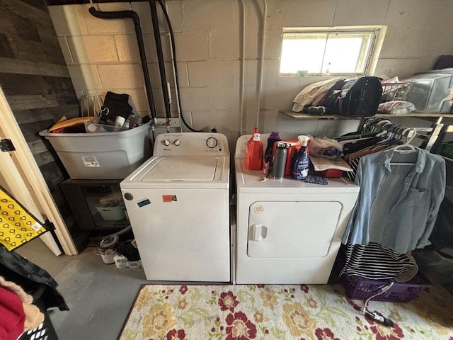 laundry area featuring concrete block wall, laundry area, and separate washer and dryer