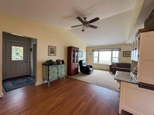 living area featuring dark wood-style flooring, ceiling fan, baseboards, and lofted ceiling
