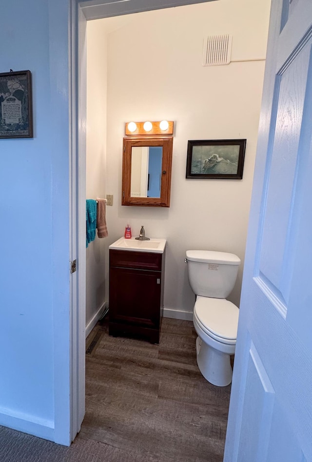 1220 N Lake Huron Shore Dr, Harrisville, MI 48740 - bathroom featuring vanity, toilet, baseboards, wood finished floors, and visible vents