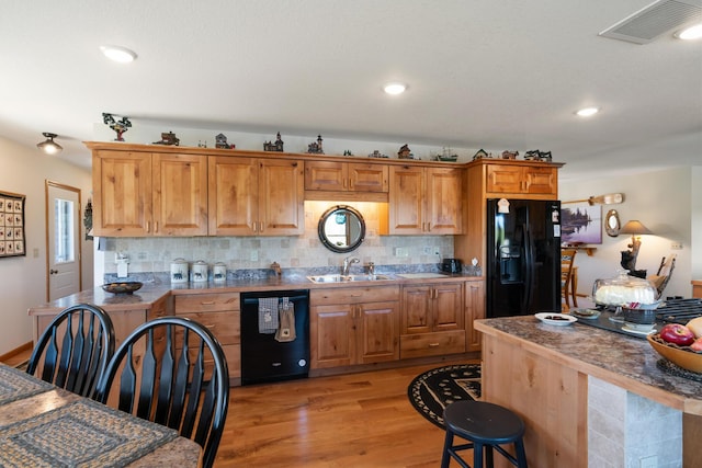 kitchen featuring light wood-type flooring, black appliances, backsplash, and visible vents