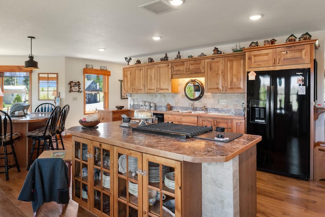 kitchen featuring black fridge, light wood-style flooring, a kitchen island, and visible vents