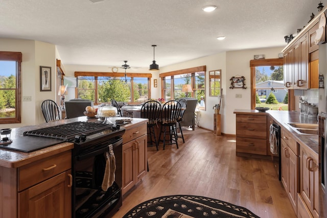 kitchen featuring brown cabinetry, black appliances, and light wood finished floors