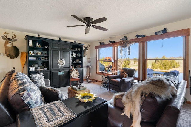 living area with a textured ceiling, baseboards, ceiling fan, and light colored carpet