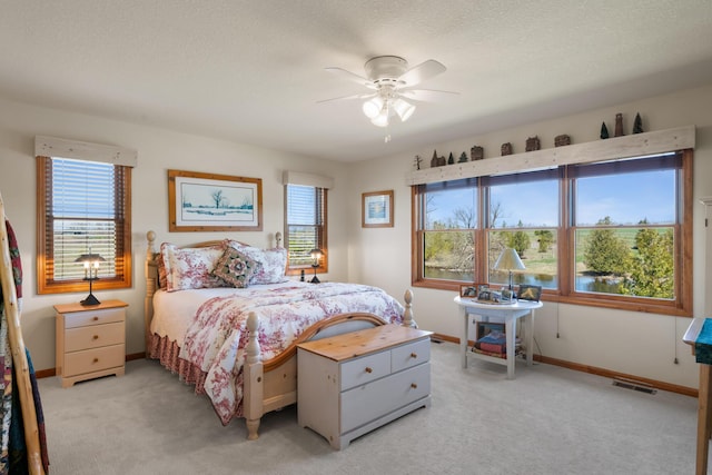 bedroom featuring light colored carpet, visible vents, baseboards, and ceiling fan