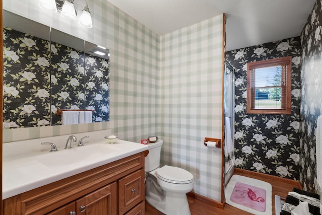 bathroom featuring toilet, a shower, wallpapered walls, and wood finished floors