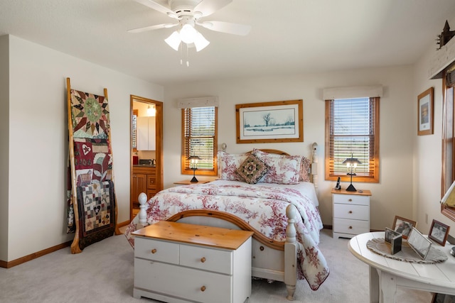 bedroom featuring baseboards, ensuite bathroom, light carpet, and ceiling fan