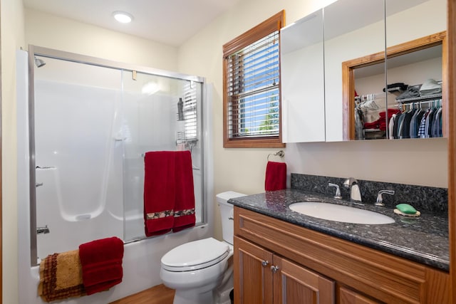 bathroom with bath / shower combo with glass door, vanity, and toilet