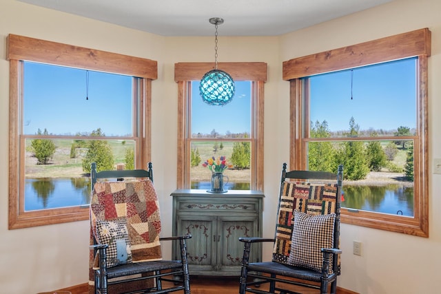 sitting room with a water view, a healthy amount of sunlight, and wood finished floors