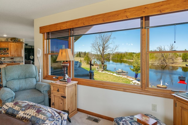 interior space with a water view, visible vents, a healthy amount of sunlight, and light carpet