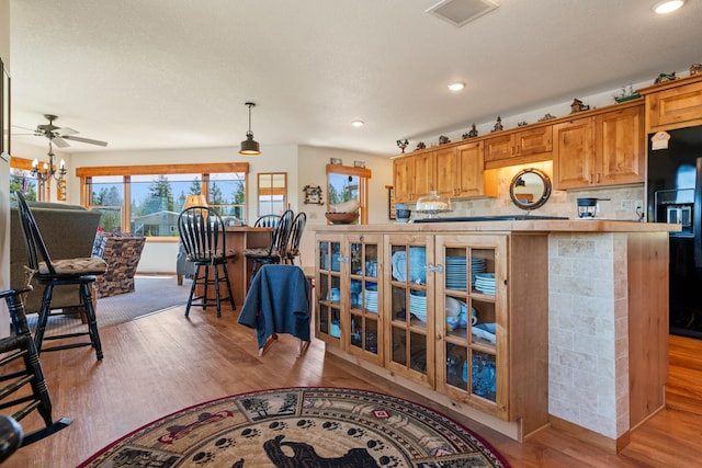kitchen featuring recessed lighting, visible vents, wood finished floors, and black refrigerator with ice dispenser