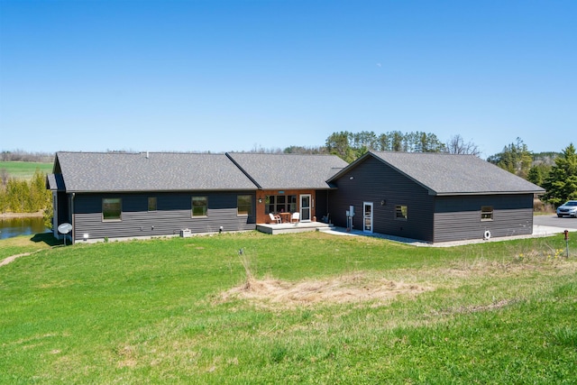 view of front facade featuring a front yard, a patio, and a shingled roof