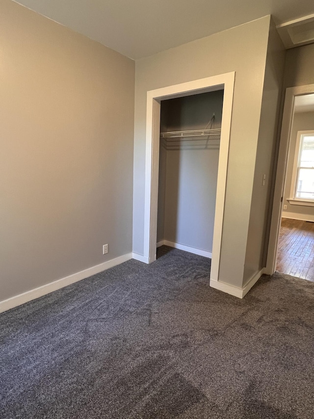 317 Pine Hill Ave, Cheboygan, MI 49721 - unfurnished bedroom featuring dark colored carpet, baseboards, and a closet