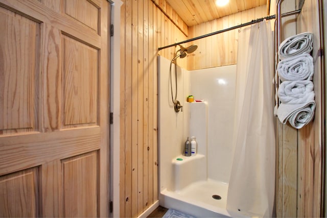 bathroom with wood walls and a shower with shower curtain