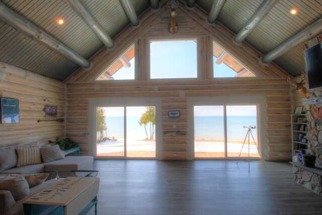 living room featuring beam ceiling, high vaulted ceiling, rustic walls, and wood finished floors