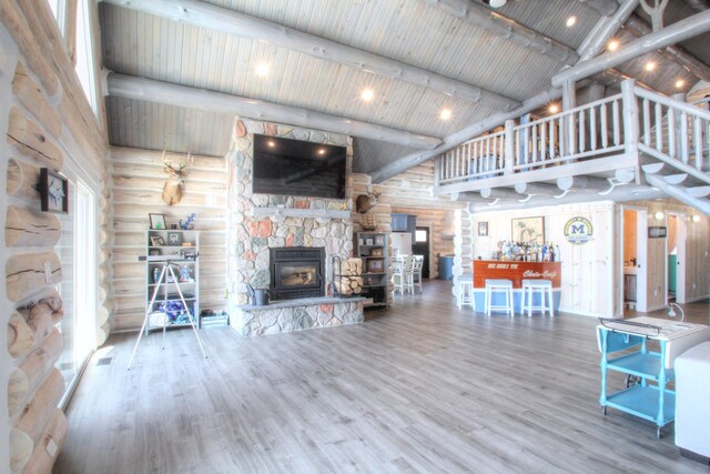 living room featuring visible vents, wood finished floors, a fireplace, beam ceiling, and high vaulted ceiling