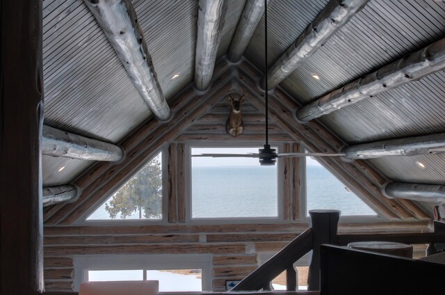 interior details with beam ceiling, wooden ceiling, a water view, and log walls