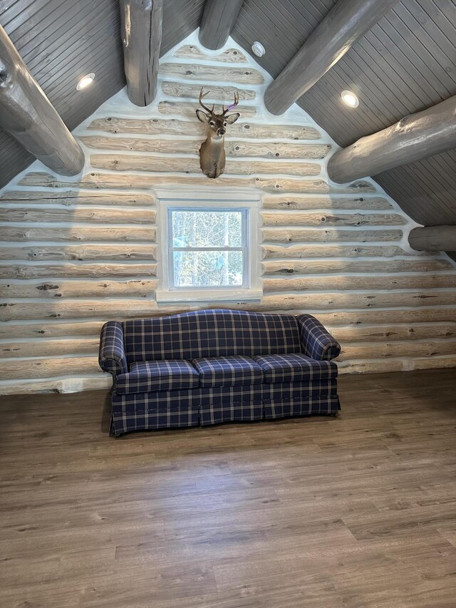 living area with rustic walls, wood finished floors, and lofted ceiling with beams