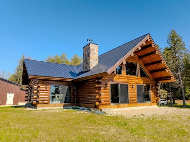 3968 Stony Pointe Rd, Hessel, MI 49745 - back of house with log siding, a chimney, a yard, and a metal roof