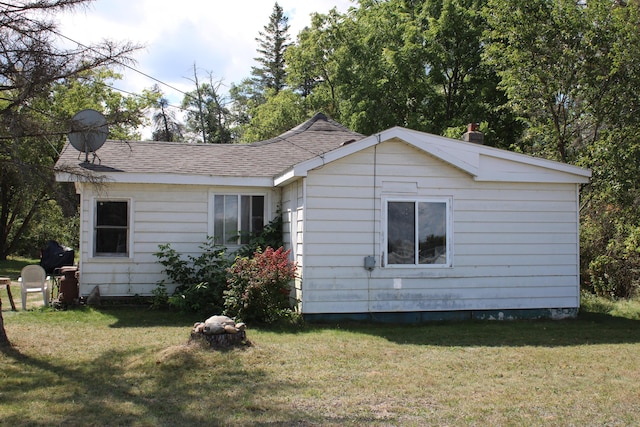 view of home's exterior with a yard and a shingled roof