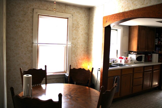 dining room featuring arched walkways and wallpapered walls