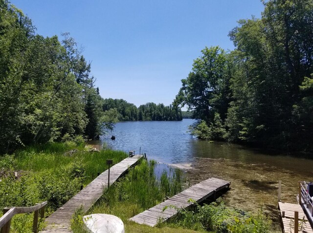 view of dock featuring a wooded view and a water view