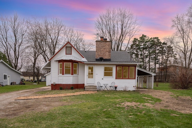 view of front facade featuring a front yard, dirt driveway, and a chimney