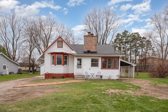 rear view of property with a chimney, entry steps, driveway, and a lawn