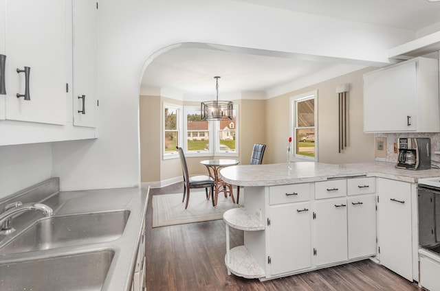 kitchen with white cabinets, a peninsula, light countertops, and a sink