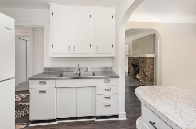 kitchen featuring white cabinetry, stainless steel counters, a sink, freestanding refrigerator, and dark wood-style flooring
