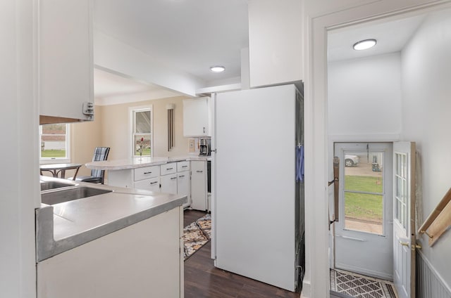 kitchen with dark wood-style flooring, white cabinets, freestanding refrigerator, and light countertops