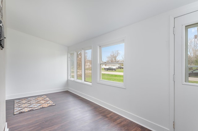 spare room featuring dark wood-style floors and baseboards
