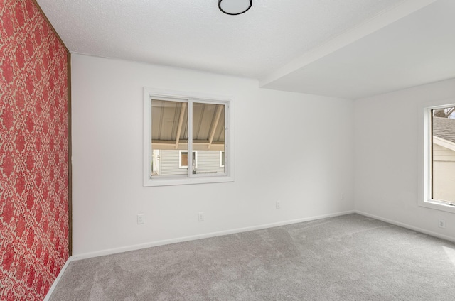 spare room with wallpapered walls, carpet, and baseboards