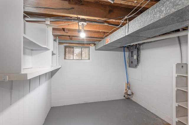basement featuring concrete block wall and electric panel