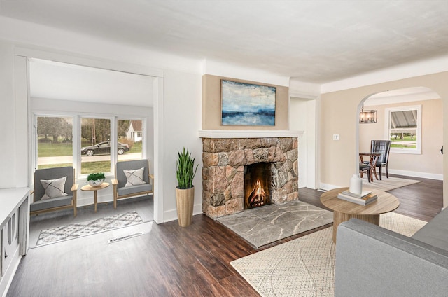 living room featuring baseboards, visible vents, arched walkways, and wood finished floors