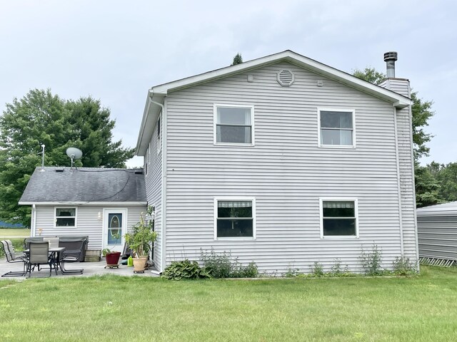 rear view of property with a lawn, a chimney, and a patio