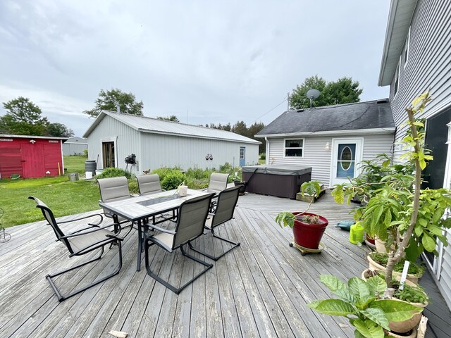 wooden terrace with an outdoor structure, outdoor dining area, a hot tub, and a yard