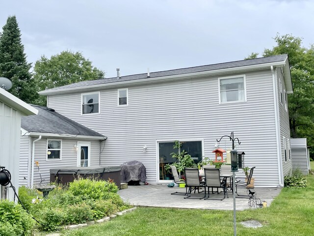 rear view of property featuring a lawn, a hot tub, a patio area, and a deck